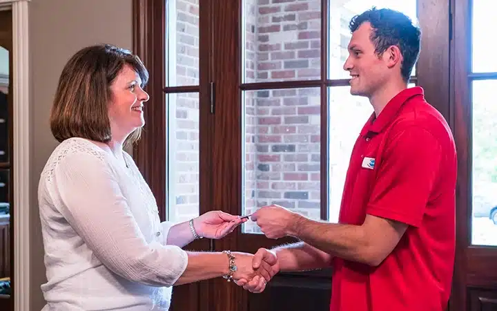 Reid and Pederson technician shaking hands with customer smiling in doorway of residential home in Crete, IL.