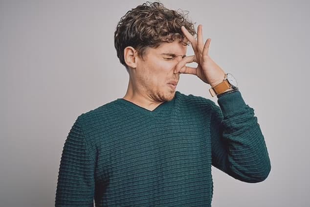 man pinching nose to avoid bad smell