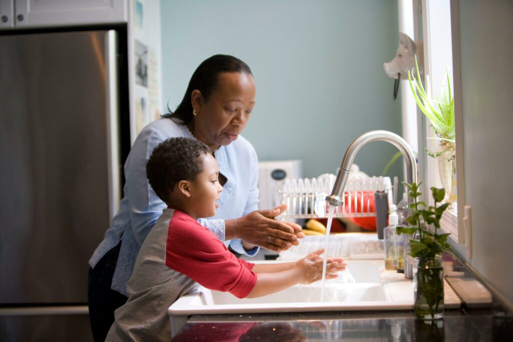 woman and child washing hands at kitchen sink