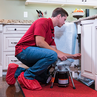 Tech inside home fixing clogged drain